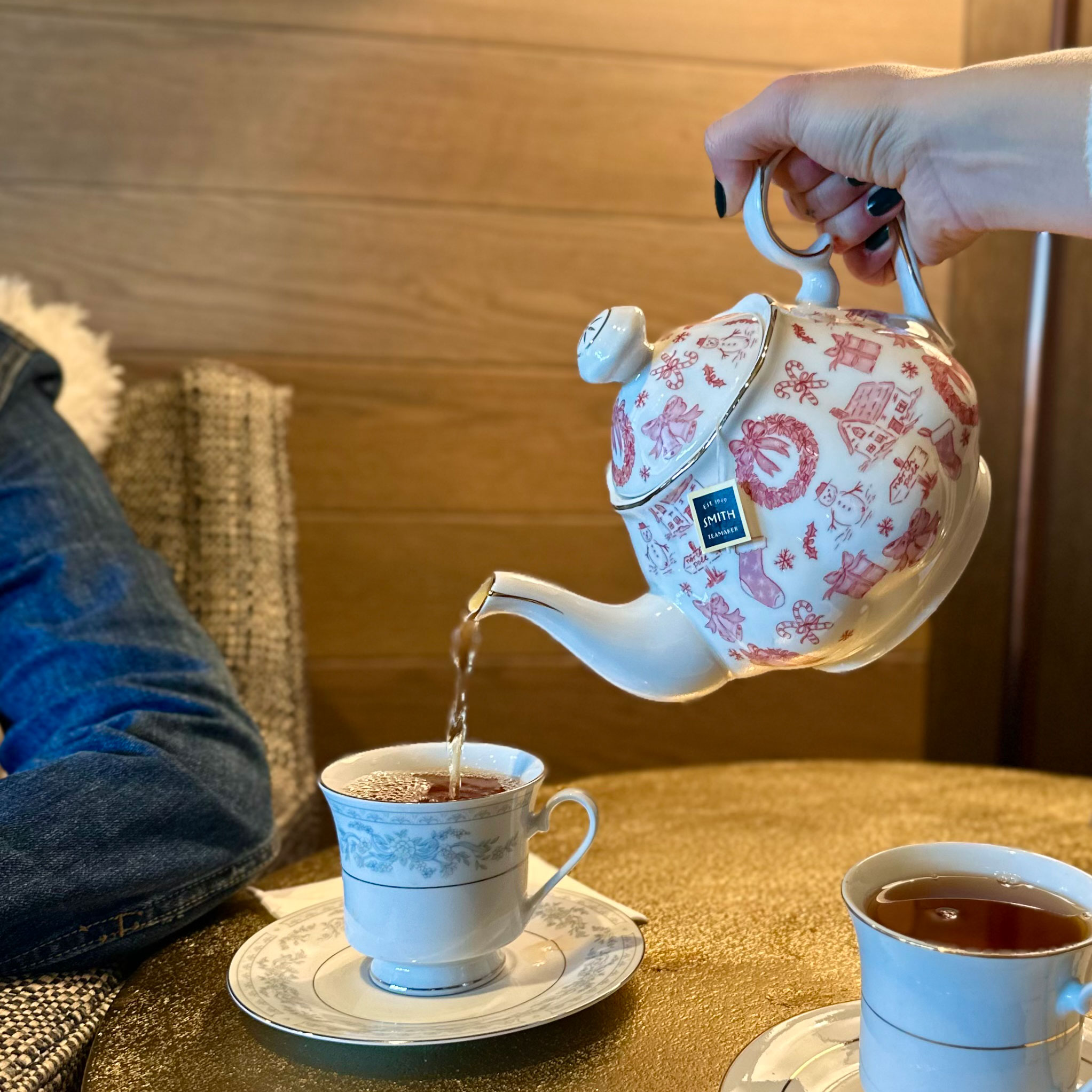 Ceramic Teapot pouring tea into tea cup on saucer.