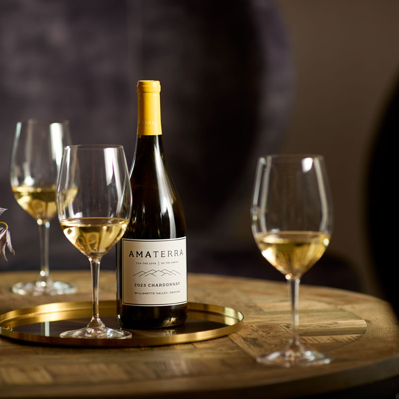 Amaterra wine bottle on a silver tray with three glasses of white wine around it.